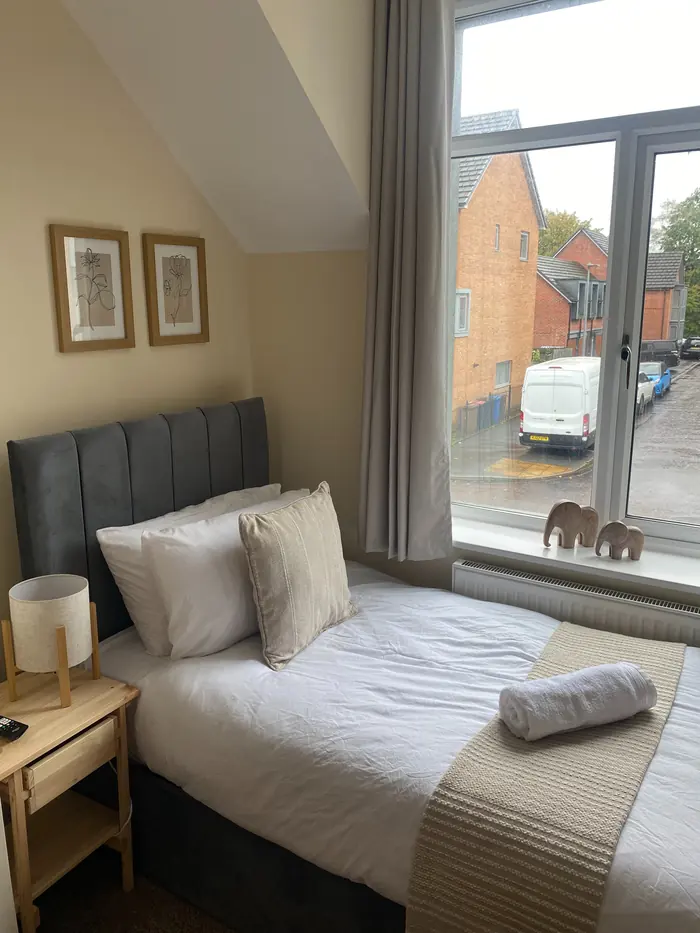 Single bed with fresh linen and a rolled towel for the next guest