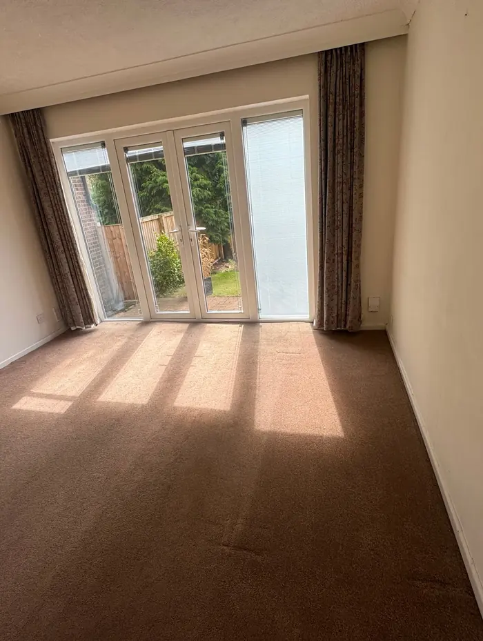 Empty carpeted room with patio doors after an end of tenancy clean